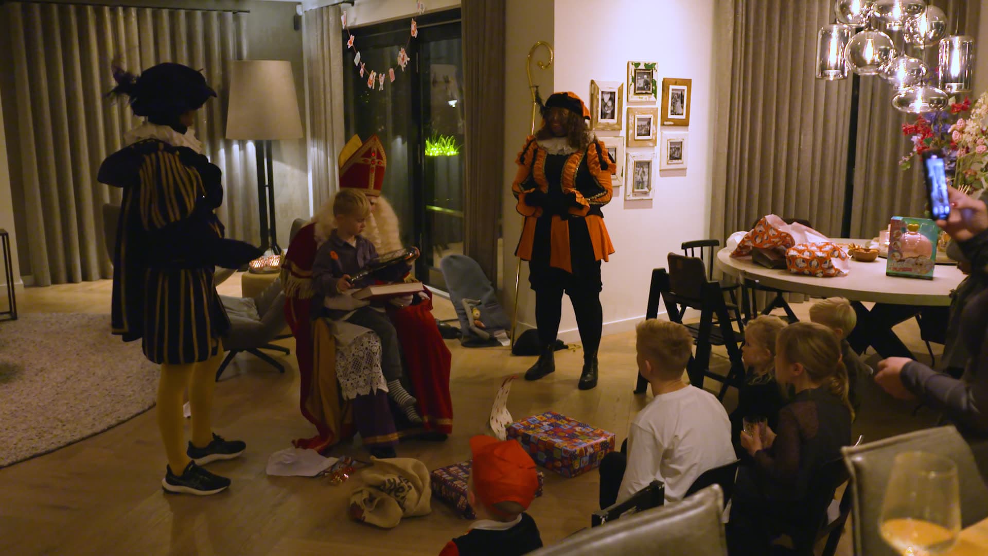 Sinterklaas overhandigt een klaargelegd cadeau tijdens een huisbezoek