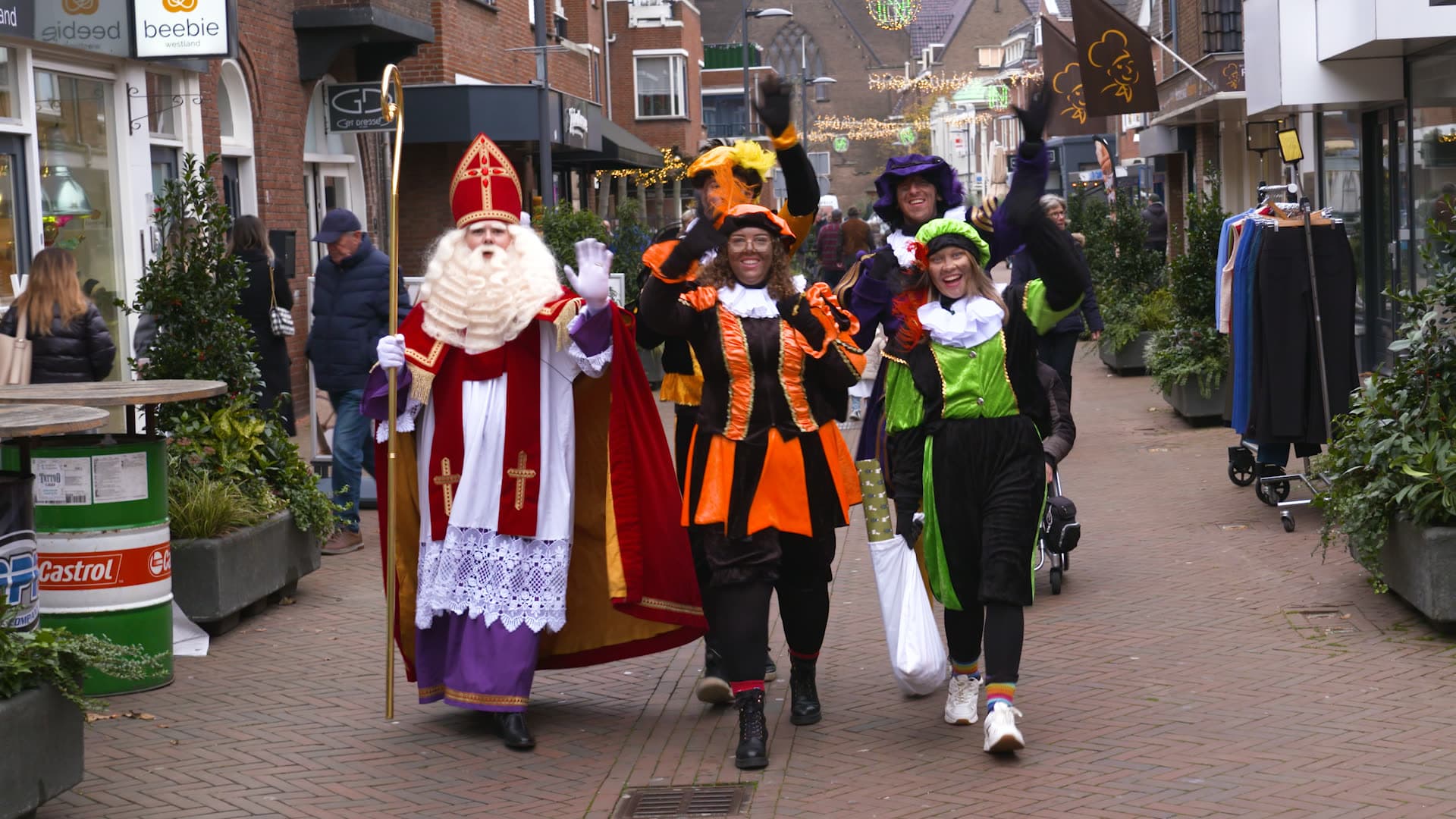 Sint en Pieten lopen zwaaiend door een winkelstraat in het Westland
